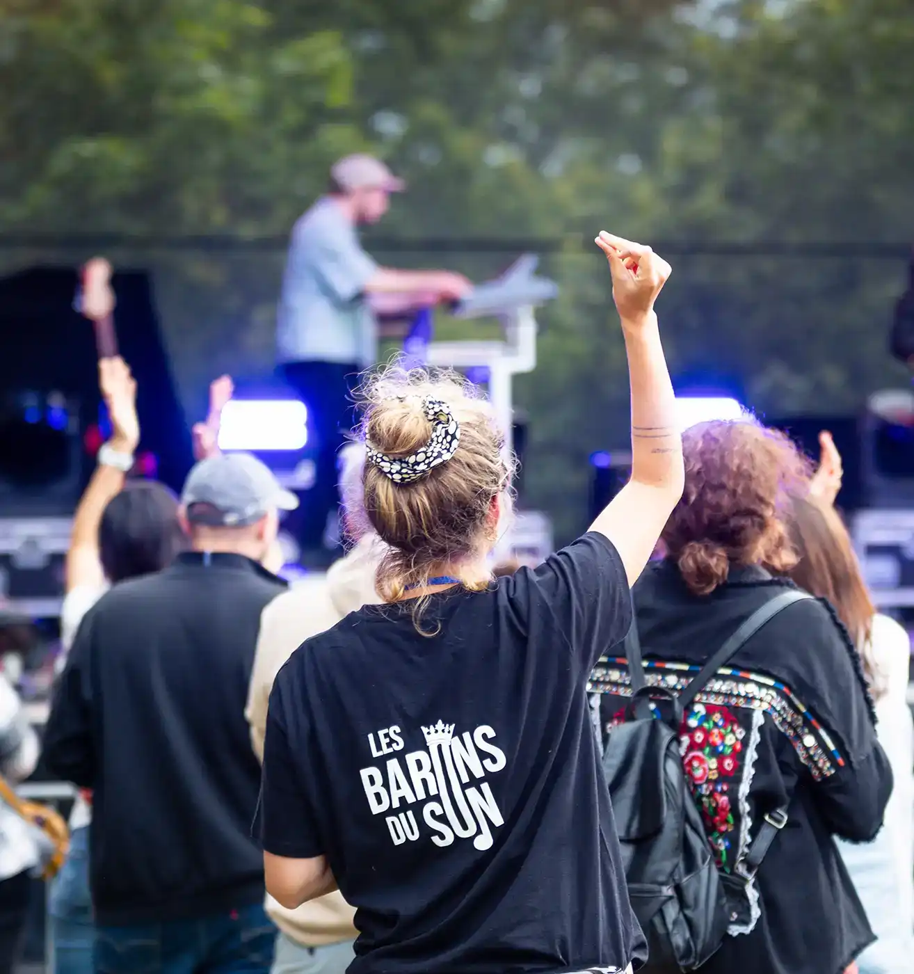 Personne de dos, bras levé vers la scène.