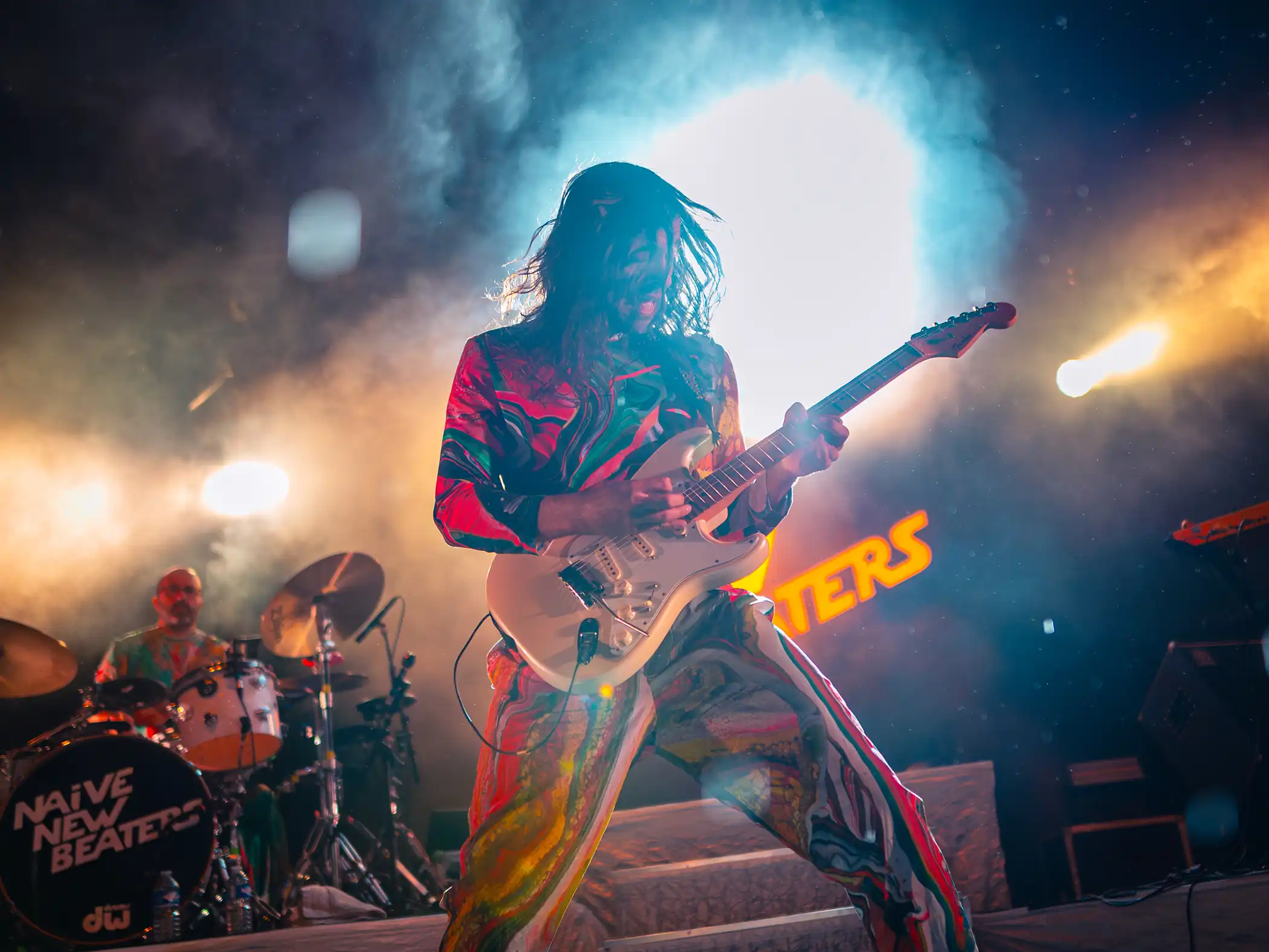 Lumières orange et foule en feu dans les vestiges du château.
